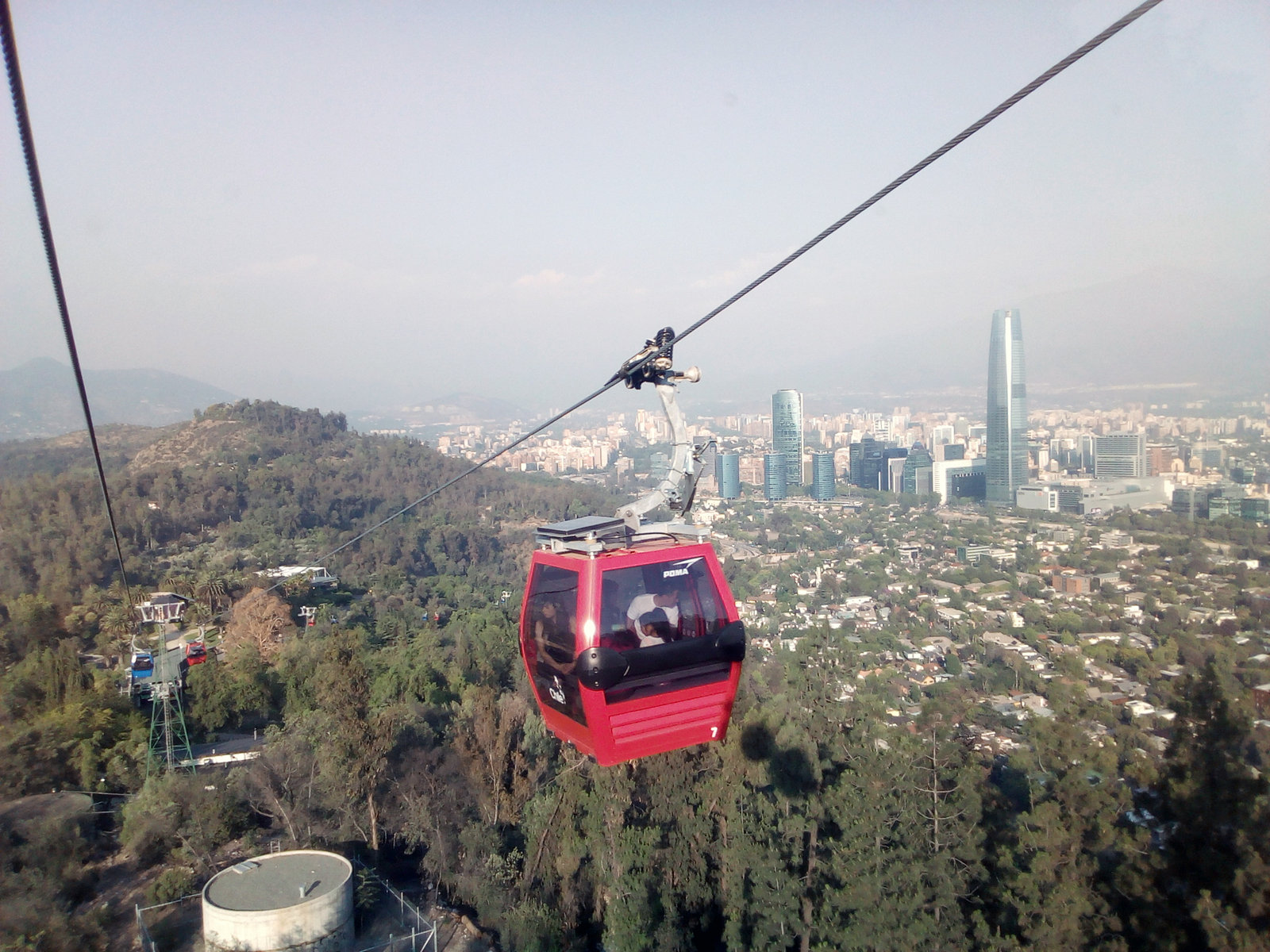 Red Santiago cable car over the green slopes of Cerro San Cristóbal